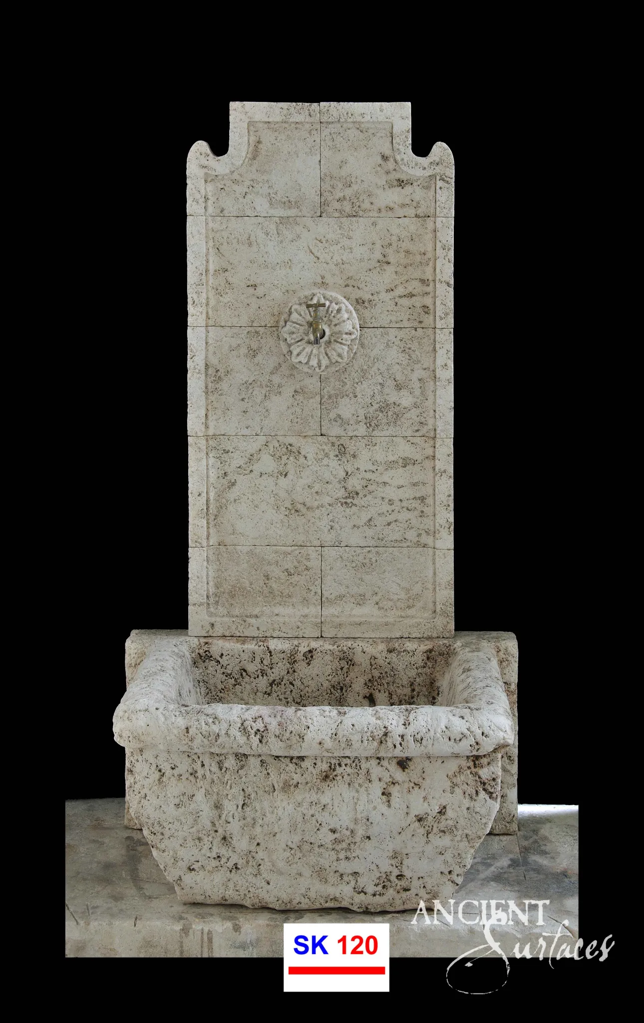 Tall reclaimed limestone wall sink with a panelled block backplate, scrolled shoulders, a carved rosette tap boss and a deep pitted rectangular trough basin