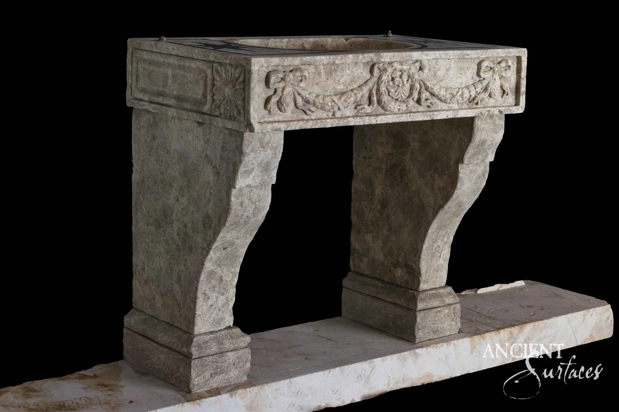 Grey reclaimed limestone console sink at three quarters, with carved ribbon bow swags on the front, a rosette at the corner and curved bracket legs on a long slab
