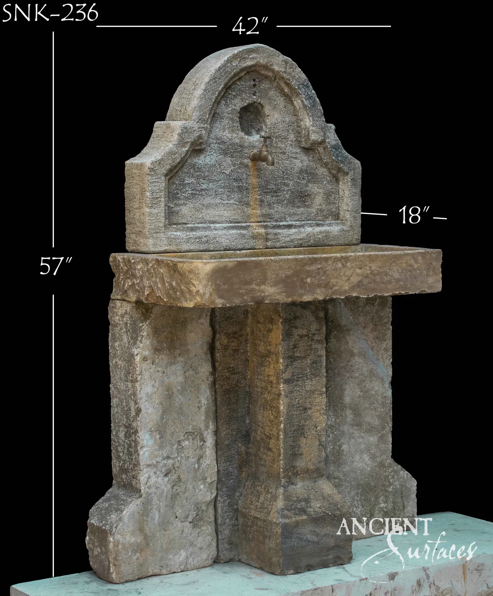 Reclaimed limestone wall sink with an arched stepped backplate, small brass tap, ochre water trail, rough chiselled rectangular basin and a pier and slab support