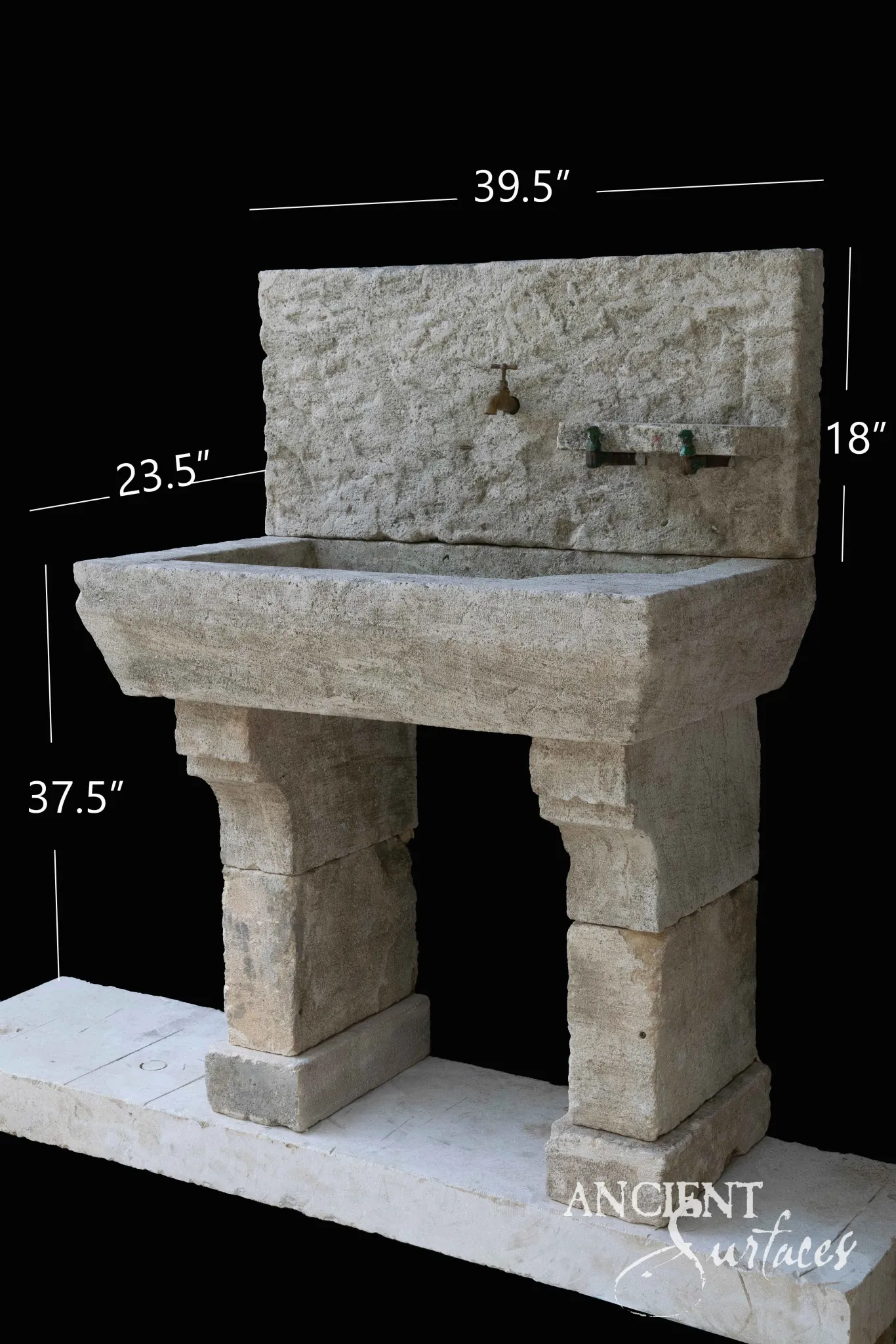 Reclaimed limestone trough sink with a rough dressed backsplash, central brass tap, a stone ledge with two weathered taps and stacked block legs on a plinth